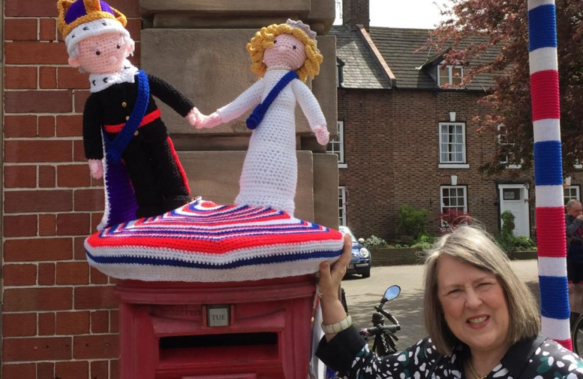 A knitted King and Queen atop a red pillar post box