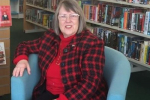 Fiona Bruce MP sitting down in a blue chair in front of library shelves