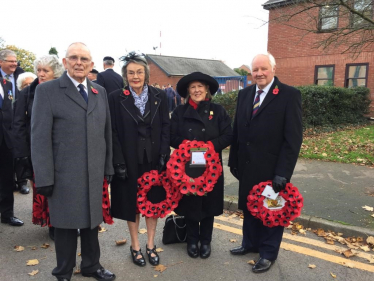 Four people gathered with poppy wreaths